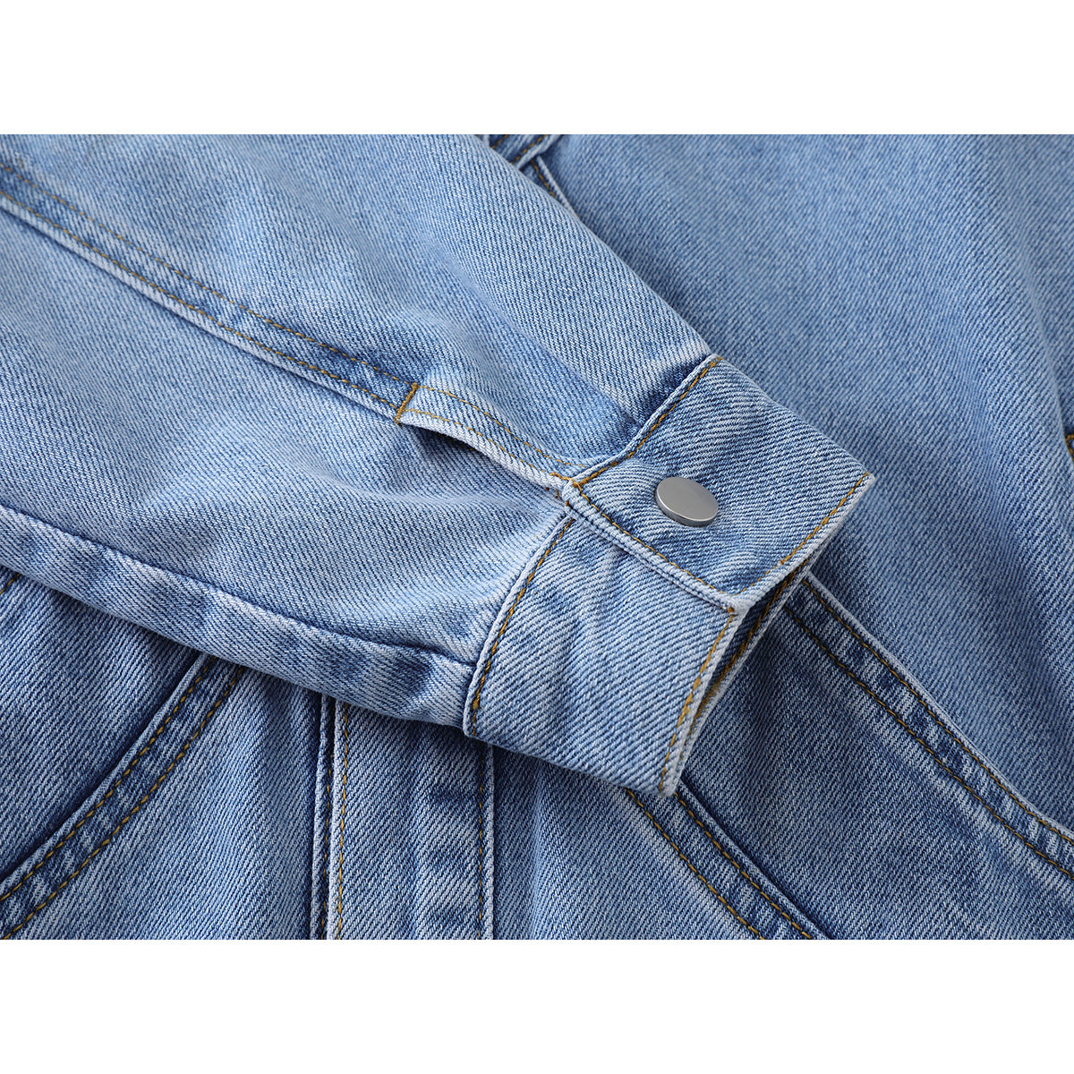 Close-up of a light blue denim jacket sleeve cuff with a silver snap and contrast stitching.