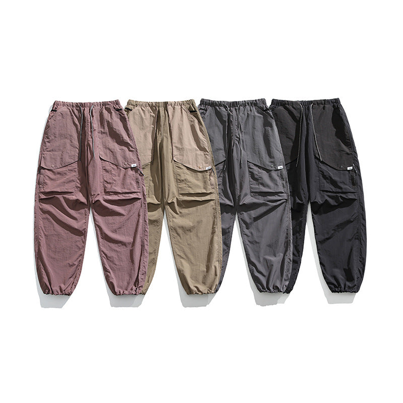 Four pairs of loose cargo pants displayed together in mauve, tan, gray, and black.