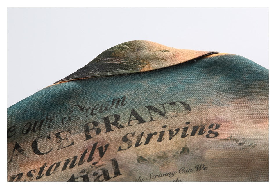 Close-up of the shirt collar and fabric, printed with a muted landscape and large black English lettering.