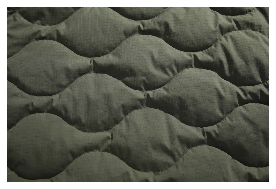 Close-up of olive padded fabric with wavy quilted sections and a fine grid texture.