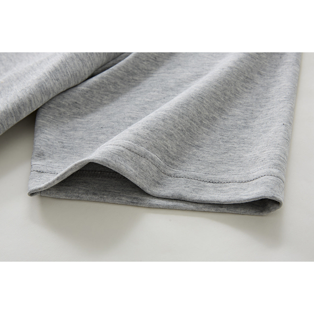 Close-up of the stitched hem on a heather gray short sleeve.