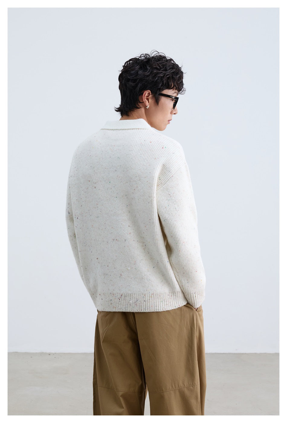 Rear view of a model wearing an ivory flecked knit polo sweater with ribbed cuffs and hem.