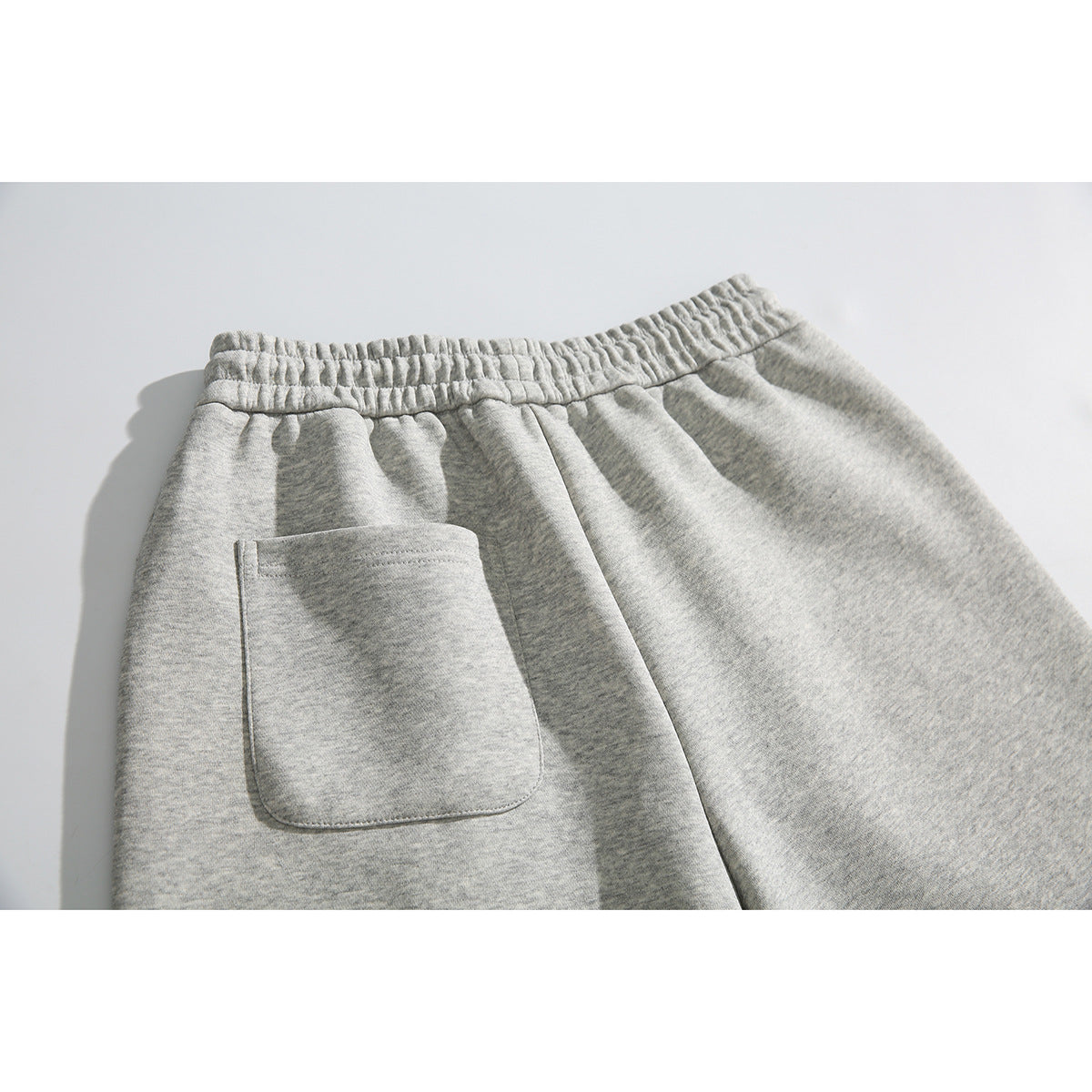 Close-up of the back of heather-gray sweatpants, showing the elastic waistband and a patch pocket.