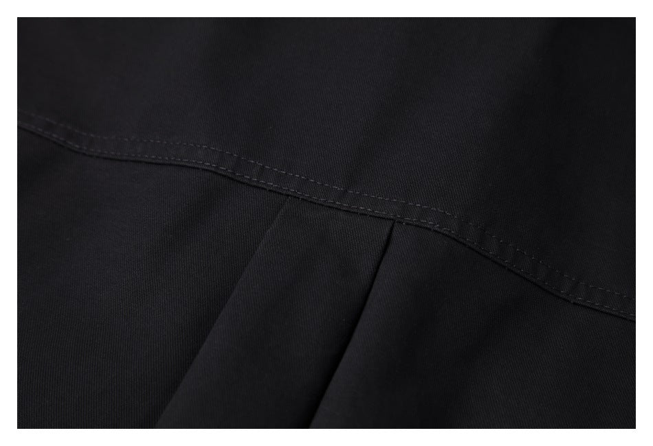 Close-up of black garment fabric showing a curved stitched seam and overlapping panels.