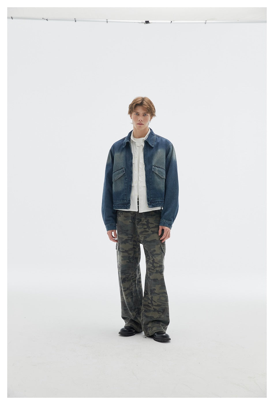 Model wearing wide-leg camouflage cargo pants with a cropped denim jacket and black boots, slightly angled front view
