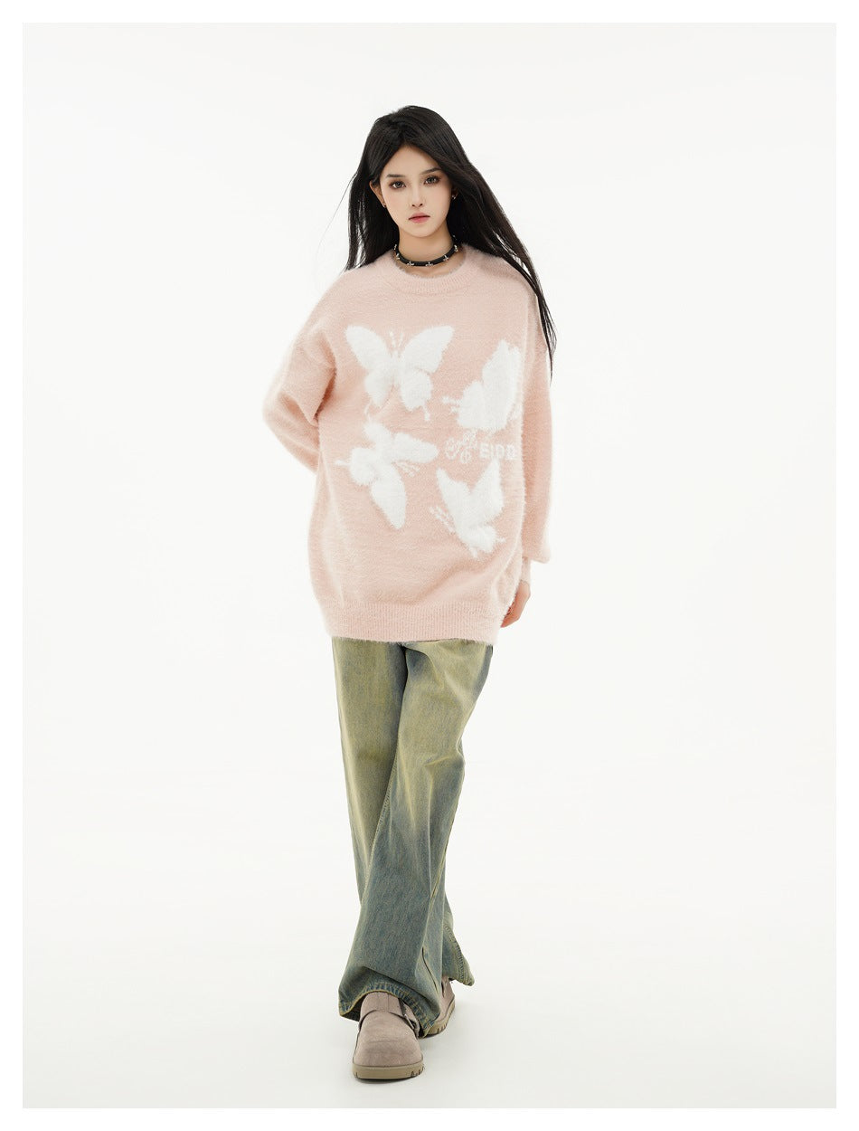 Front view of a model in a blush-pink oversized sweater with white butterfly motifs and olive wide-leg jeans.