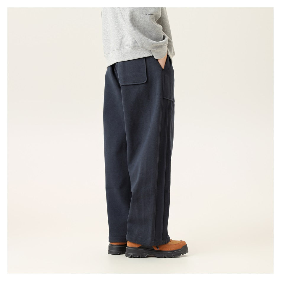 Side view of a person wearing navy wide-leg sweatpants with a gray sweatshirt, hand in pocket