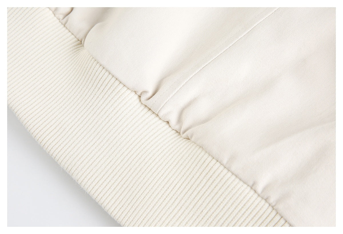 Close-up of an ivory garment showing a wide ribbed cuff joined to smooth fabric.