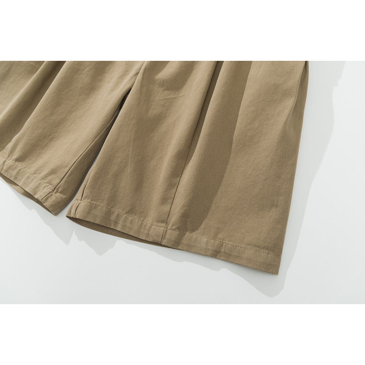 Close-up of the wide-leg hems and stitching on khaki shorts.