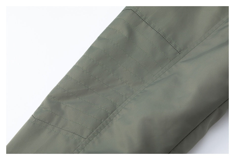 Close-up of parallel stitched bands on the sleeve of an olive-gray garment.