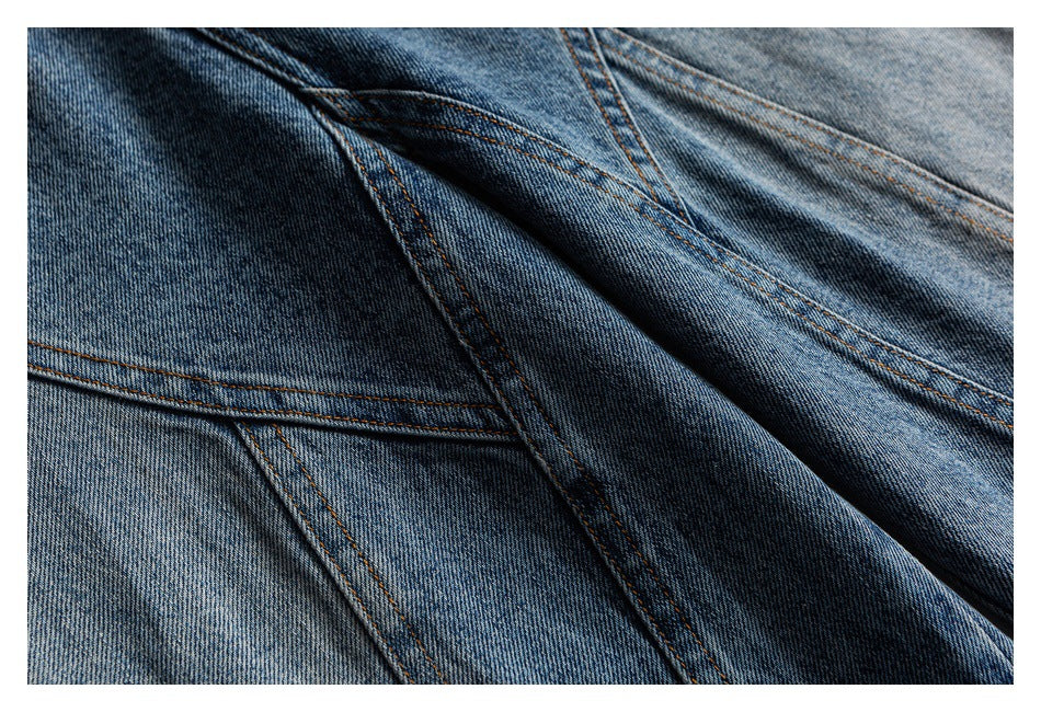 Close-up of blue denim with intersecting seams and contrasting orange topstitching.