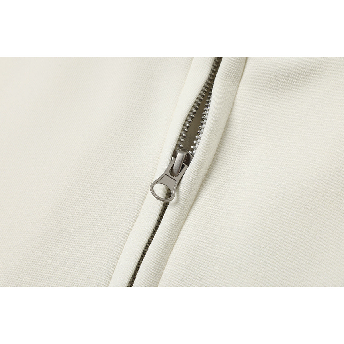 Close-up of the metal zipper and pull on ivory jacket fabric.
