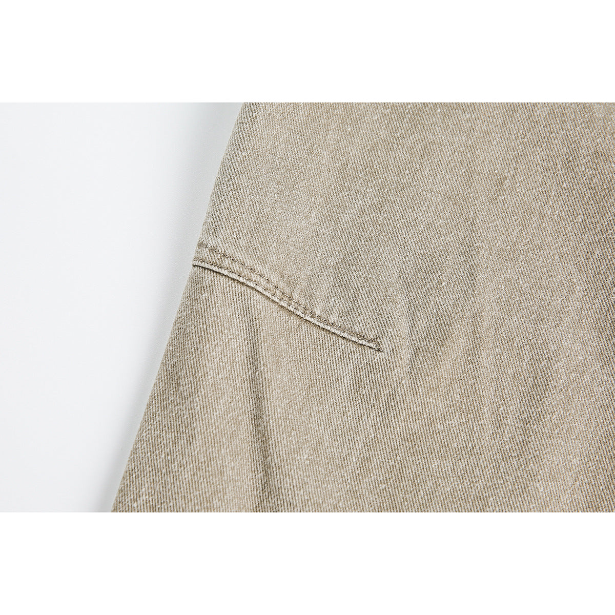 Close-up of light beige pants showing a stitched seam against the textured fabric.