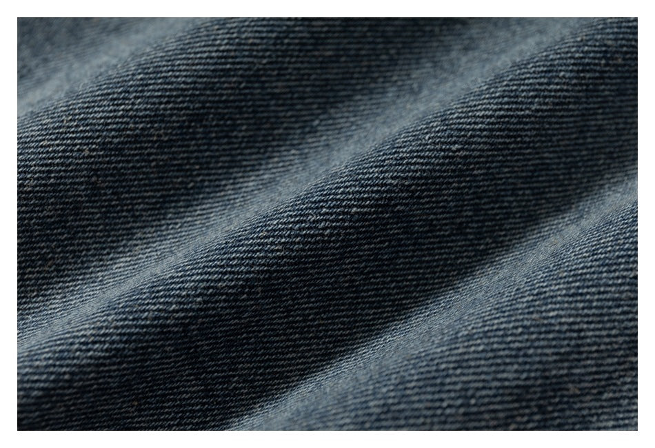 Macro view of the dark blue denim fabric weave and faded ridges.