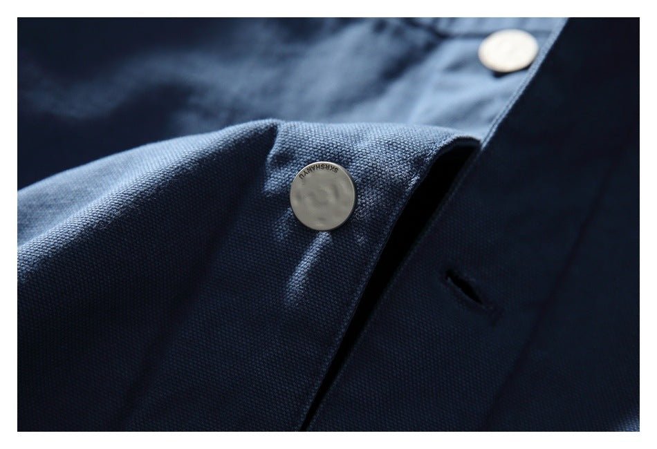 Close-up of dark blue garment fabric with pale round buttons and a buttonhole.