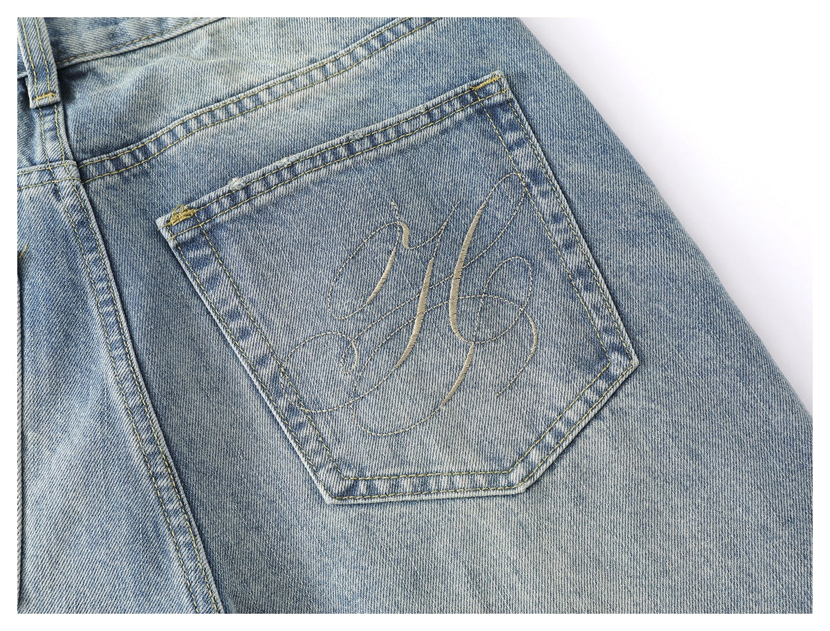 Close-up of a back pocket on faded blue jeans, with decorative curved stitching.