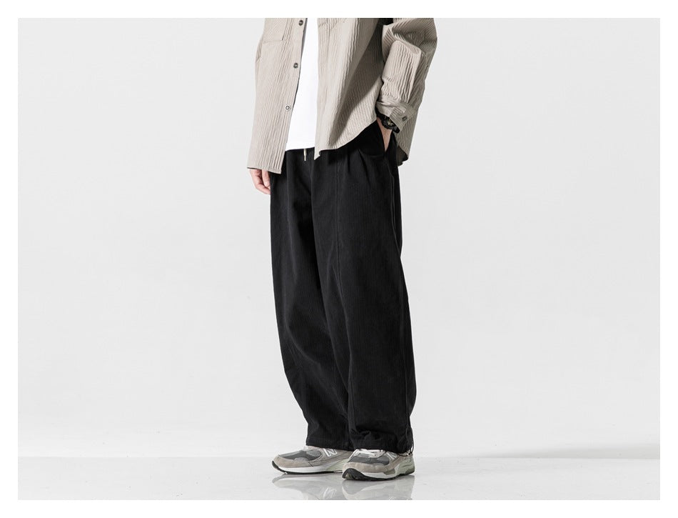 Cropped model standing in black wide-leg pants with a loose fit and adjustable hems.
