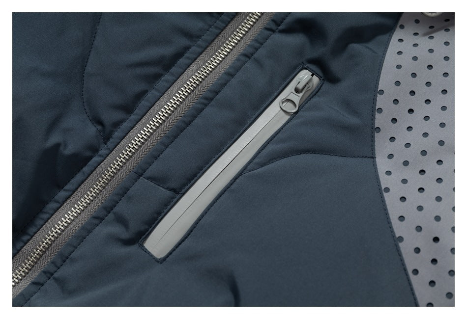 Close-up of a dark slate jacket showing its main zipper, slanted gray pocket zipper, and perforated gray panel.