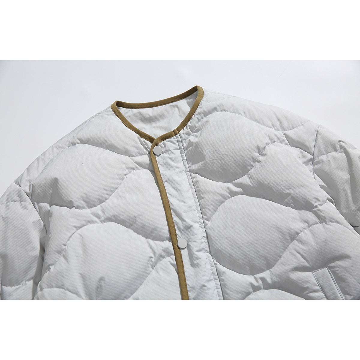 Close-up of a pale gray quilted jacket with a snap-front opening and olive-brown trim around the neckline and placket.
