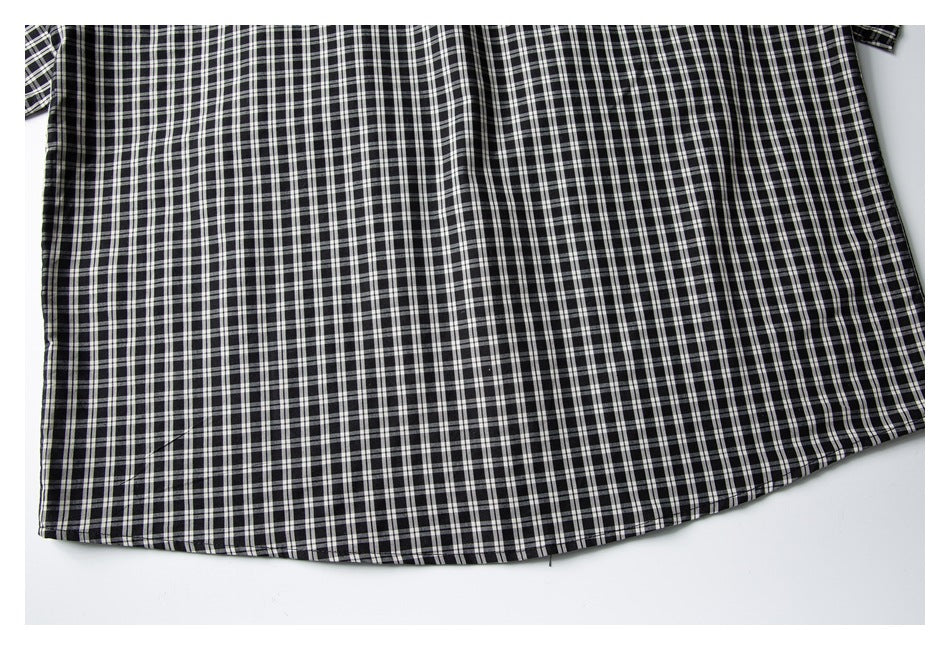 Close-up of the curved hem and lower body of a black-and-white plaid shirt.