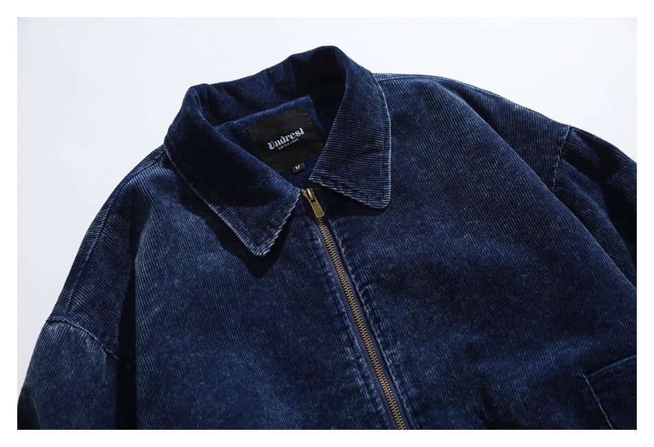 Close front view of a dark navy ribbed jacket with a pointed collar and gold-tone zipper.