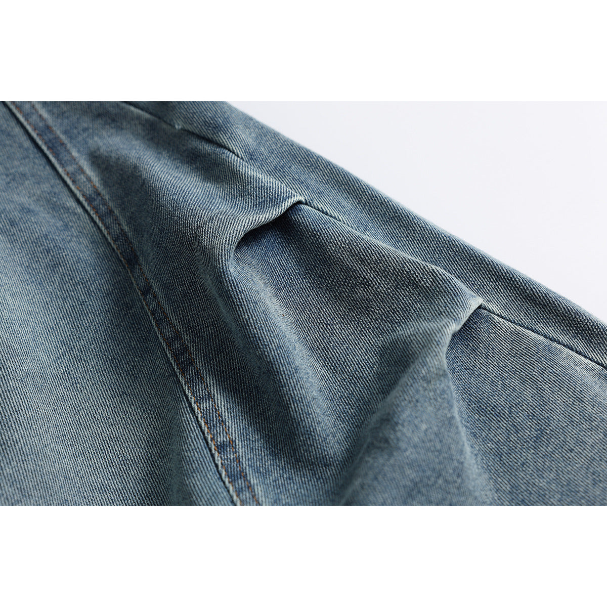Close-up of folded blue-gray denim with visible diagonal weave and stitched seam.
