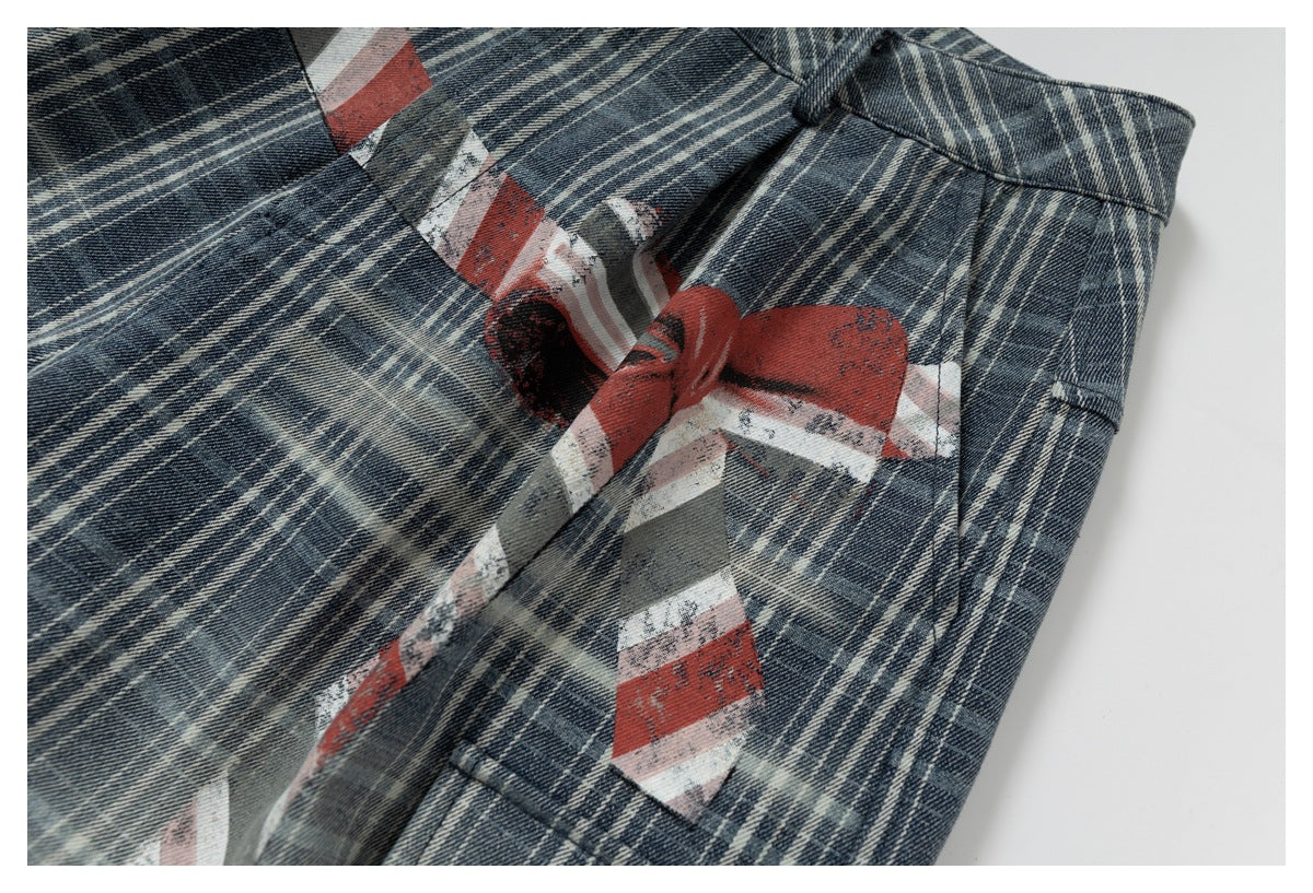 Close-up of dark blue and cream plaid trousers with a distressed red, white, and gray graphic print.