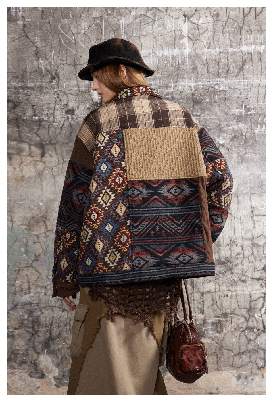 Back view of a model wearing a patchwork jacket with plaid, geometric-print, and textured tan panels.