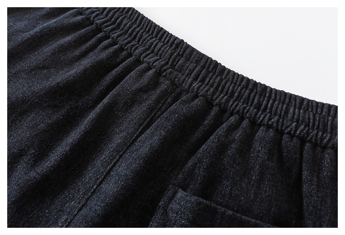 Close-up of black pants with a gathered elastic waistband and the top edge of a pocket.
