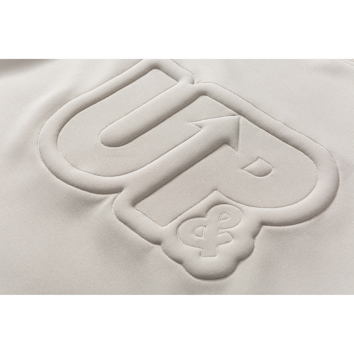 Close-up of a raised tonal logo on light beige fabric.