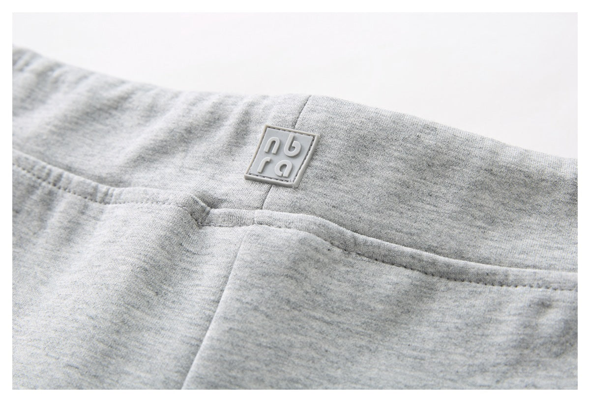 Close-up of the gray shorts’ waistband, center seam, stitching, and small square logo patch.