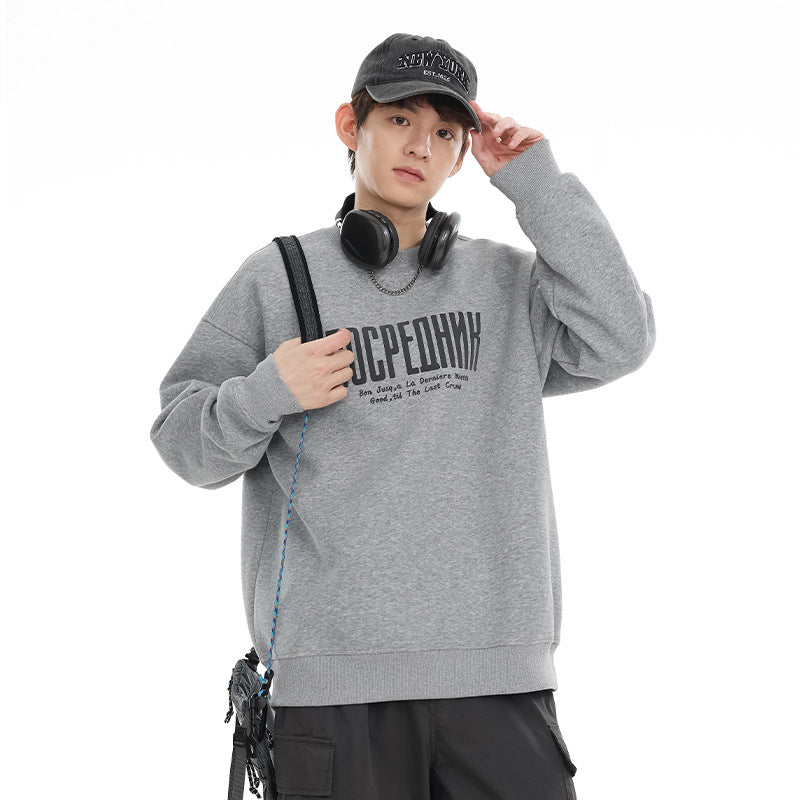 Model wearing a light gray crewneck sweatshirt with dark chest lettering and ribbed trim.