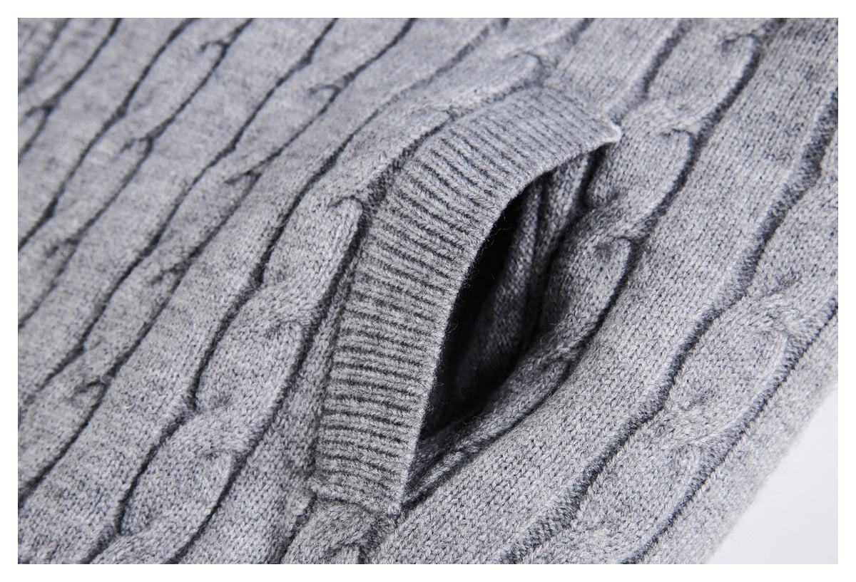 Close-up of a pocket opening edged with ribbed knit on a gray cable-knit sweater.