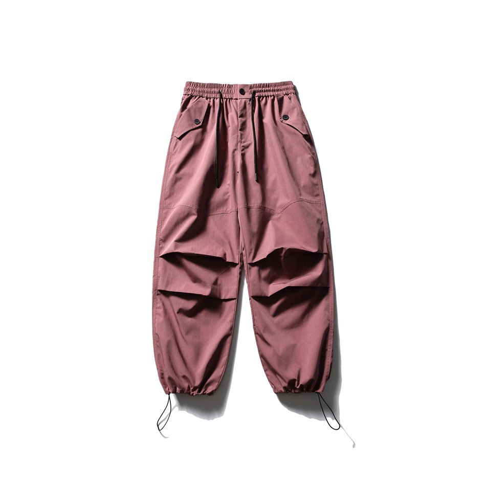 Front view of dusty rose utility pants with an elastic drawstring waist, flap pockets, knee pleats, and ankle cords.