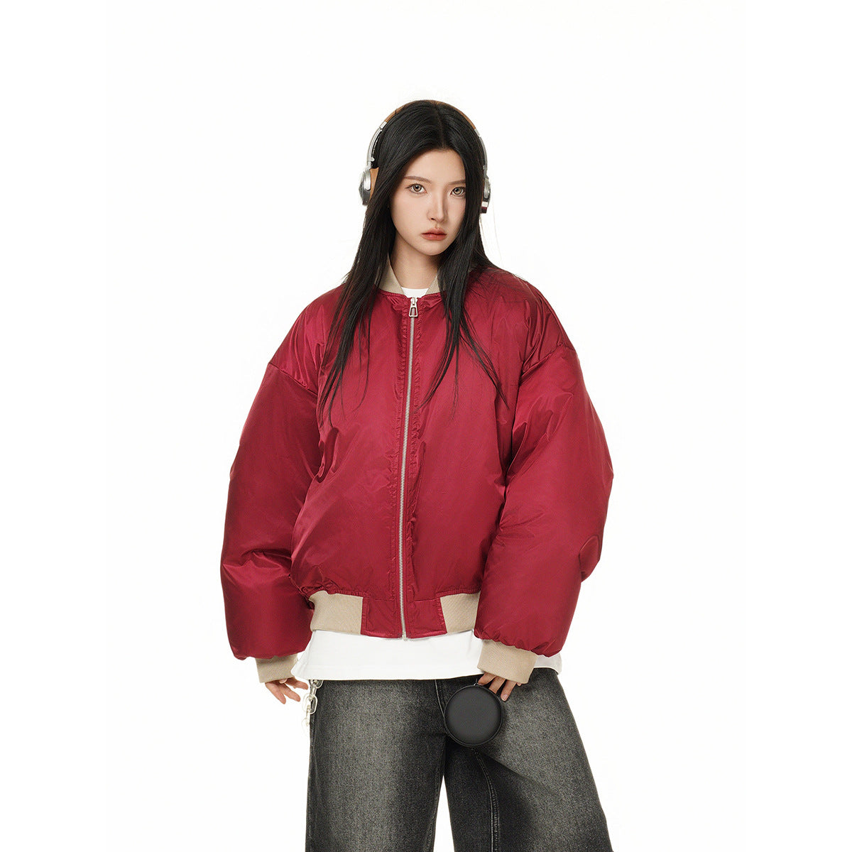 Model wearing a red oversized bomber jacket with a front zipper and beige ribbed trim, shown from the waist up.