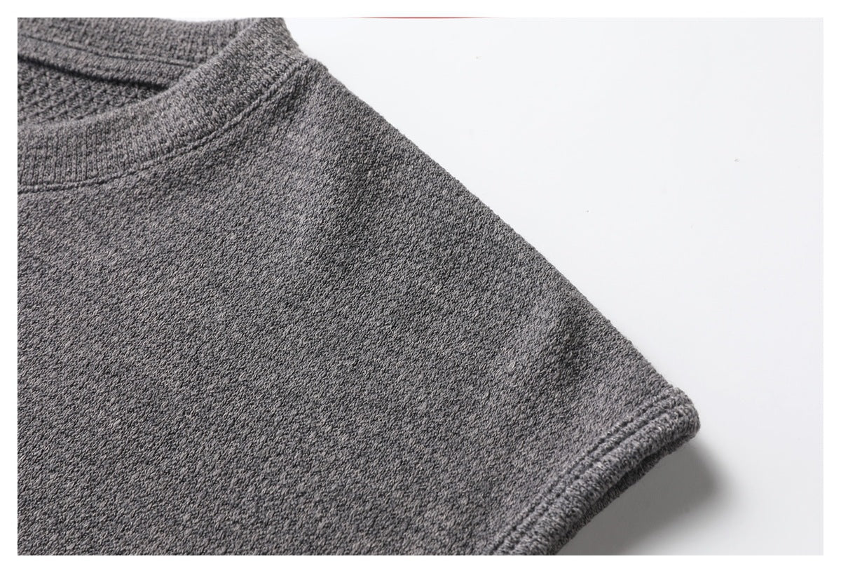 Close-up of the gray top's textured fabric and stitched shoulder edge beside the neckline.
