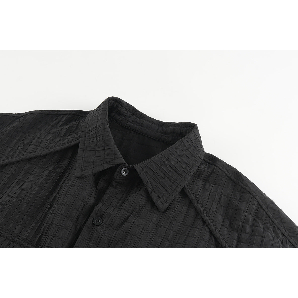 Close-up of a black shirt’s pointed collar, button placket, and subtly textured fabric.