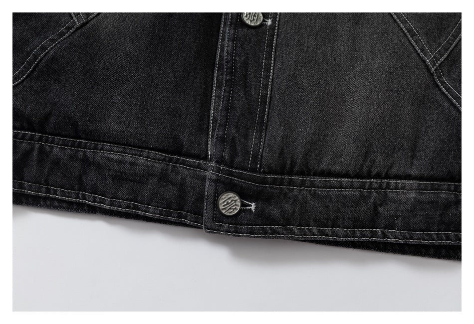 Close-up of the black denim jacket's buttoned lower hem and contrast stitching.