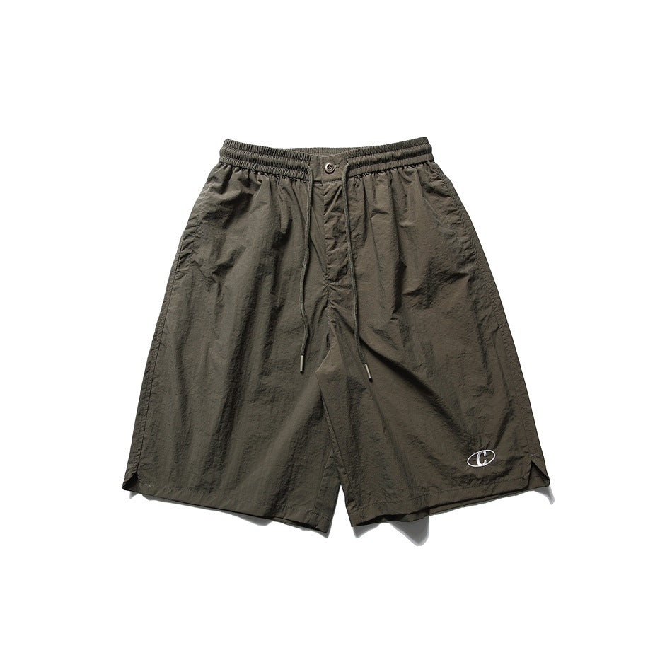 Olive green knee-length drawstring shorts with elastic waist and small embroidered oval logo, flat front view