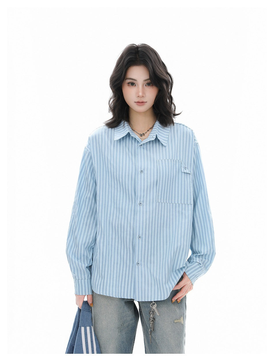 Model wearing a light blue striped oversized button-up shirt with chest pocket and distressed jeans, front view