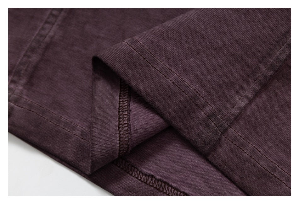 Close-up of a dark plum garment hem showing double stitching and interior overlock seams.