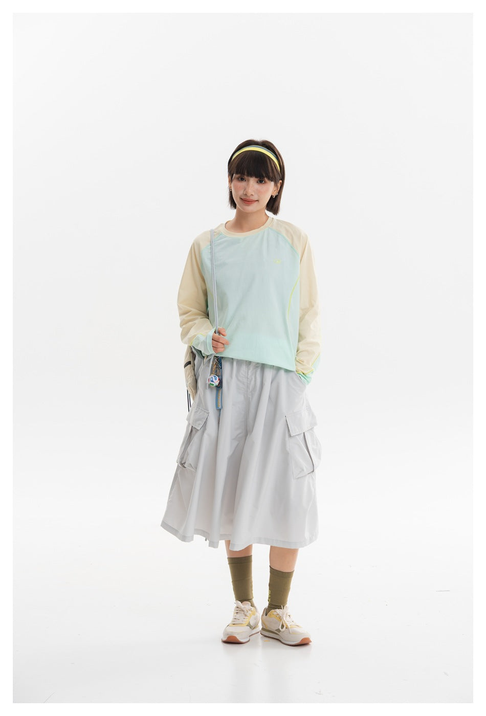 Model wearing a pale mint and cream long-sleeve top with a light gray midi cargo skirt.