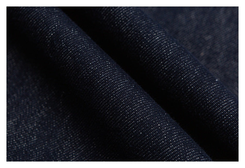 Macro view of dark indigo denim folded to show its woven texture.