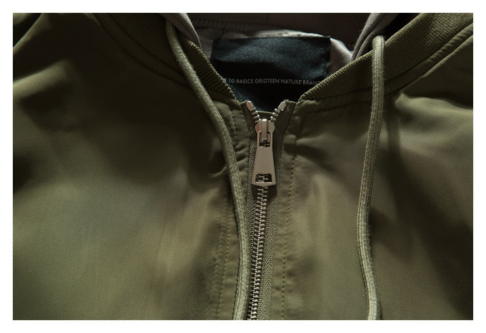 Close-up of an olive hooded jacket with a metal front zipper, drawstrings, and a small inner neck label.