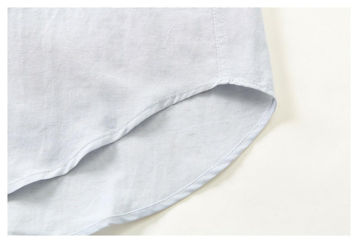 Close-up of the curved, stitched hem of a pale blue-gray shirt.