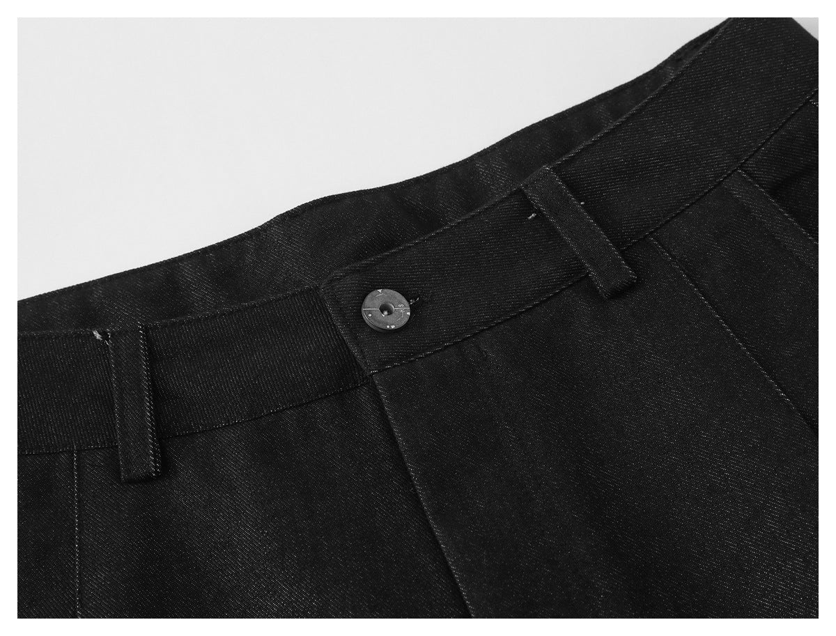 Close-up of black trousers showing the waistband, button, and belt loops.