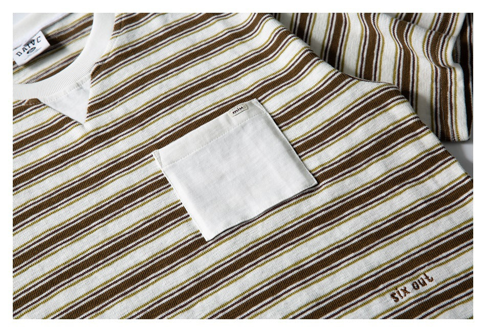 Close-up of a cream V-neck striped shirt showing its white chest pocket, collar, and small embroidered lettering.