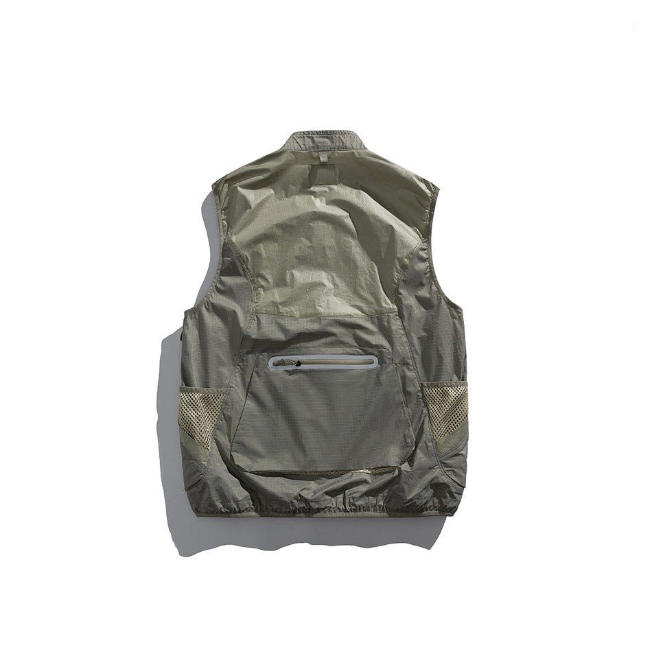 Back view of an olive-gray utility vest with mesh side pockets and a horizontal zip pocket.