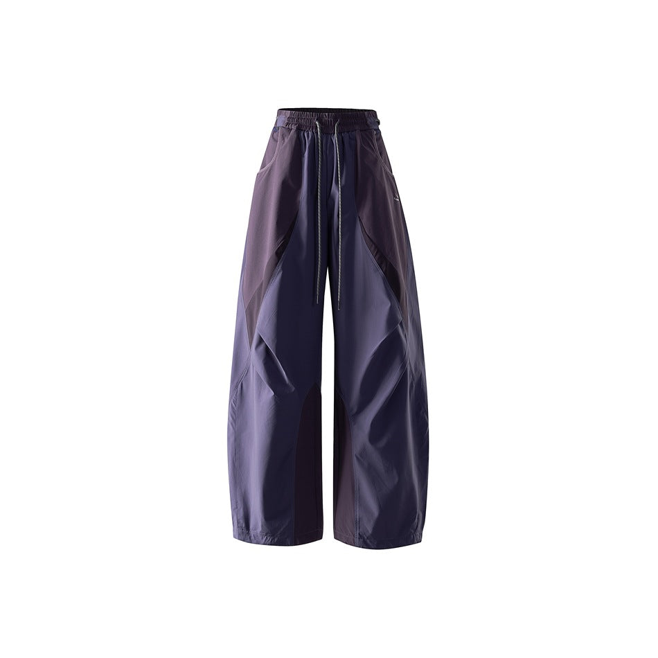 Purple wide-leg drawstring pants with darker plum curved panels, shown flat from the front