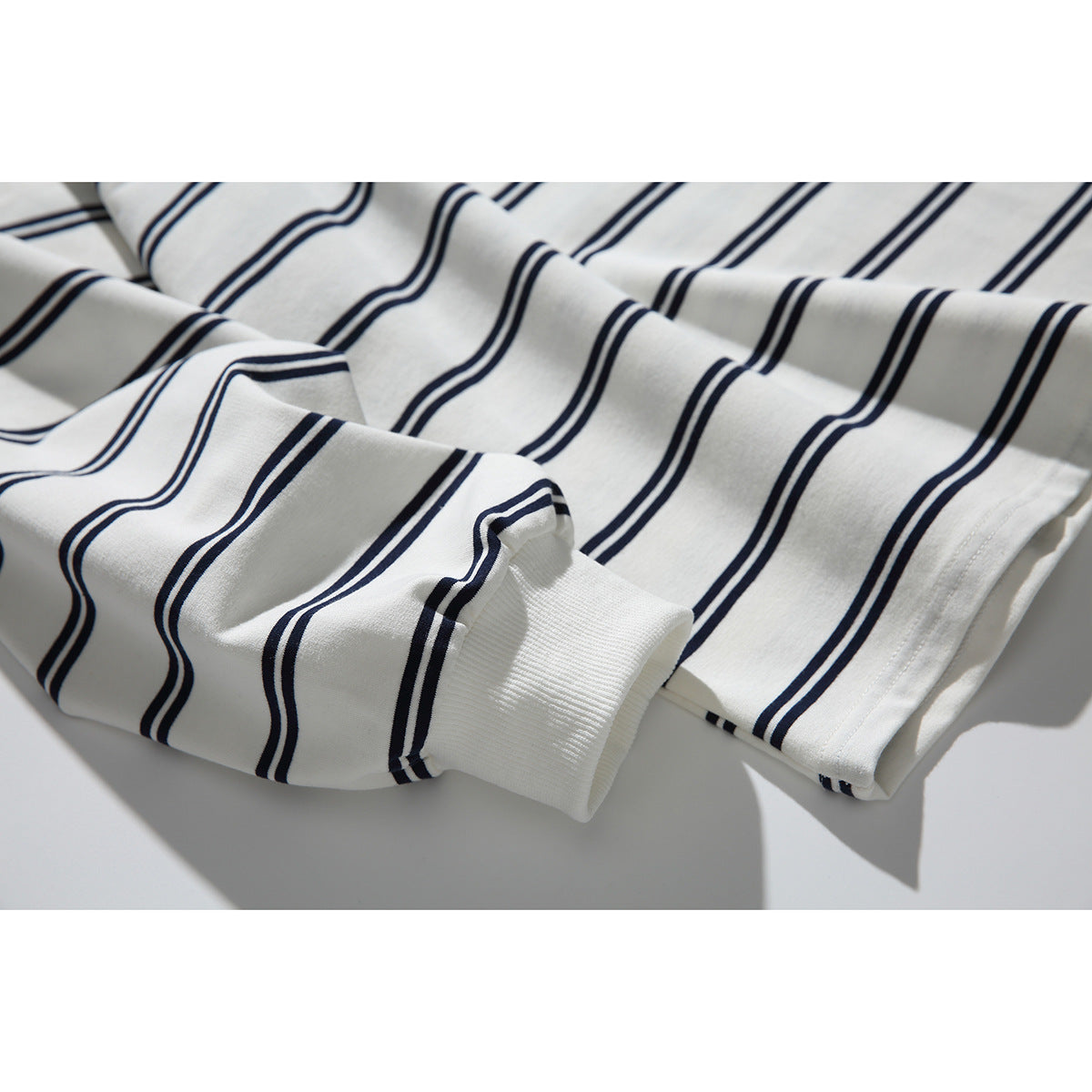 Close-up of the ivory shirt’s navy-striped sleeve, ribbed cuff, and hem.